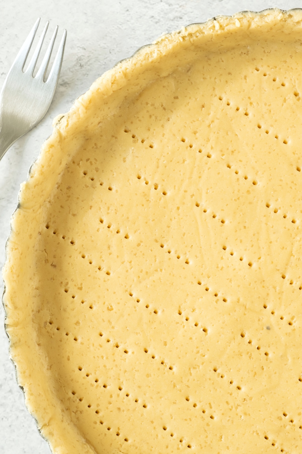 Up close shot of a gluten-free pie dough poked with holes.