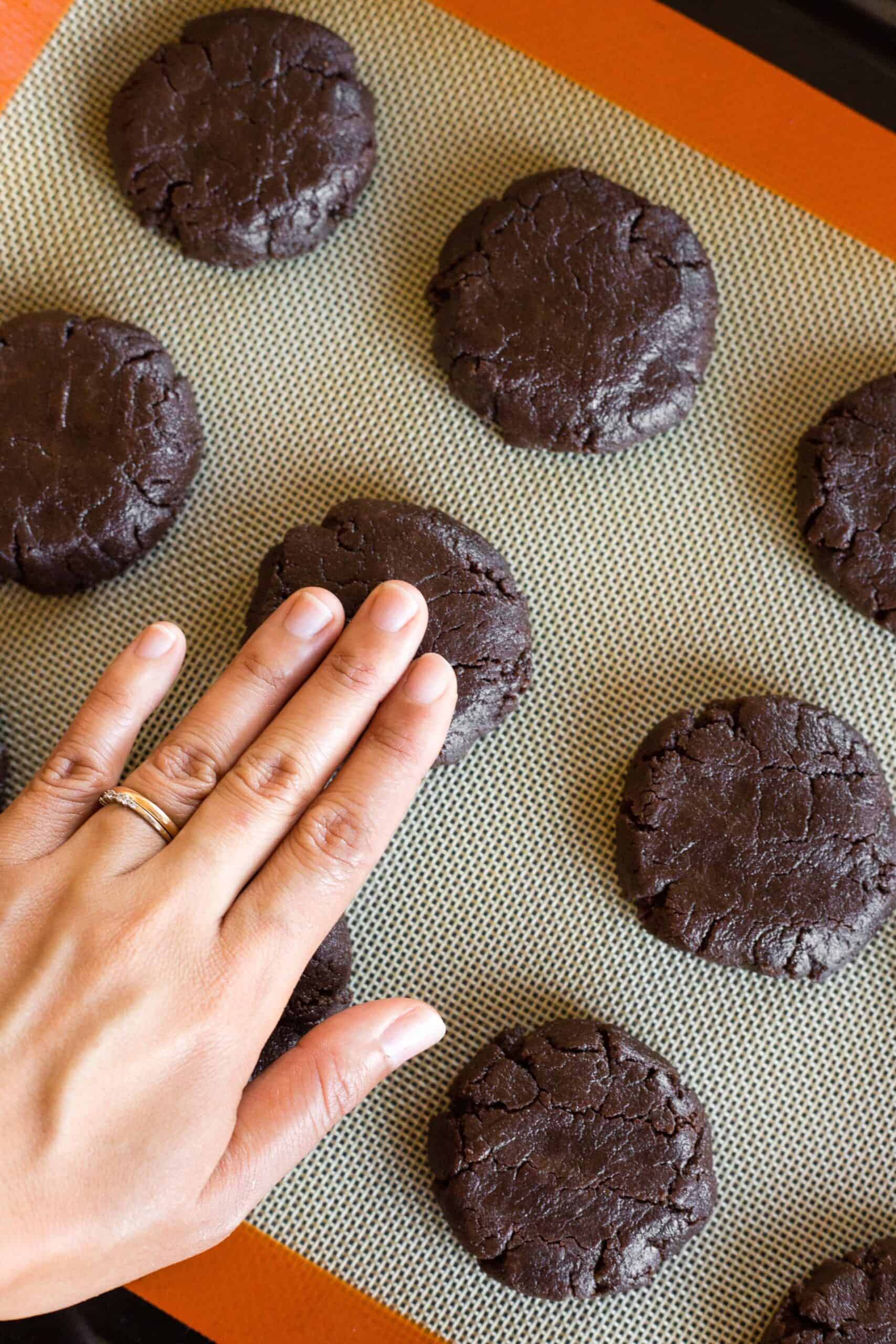 Using fingers to flatten down cookie dough.