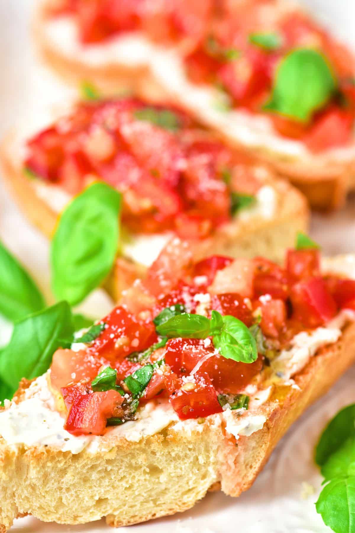 Up close view of bruschetta topped with tomato and basil