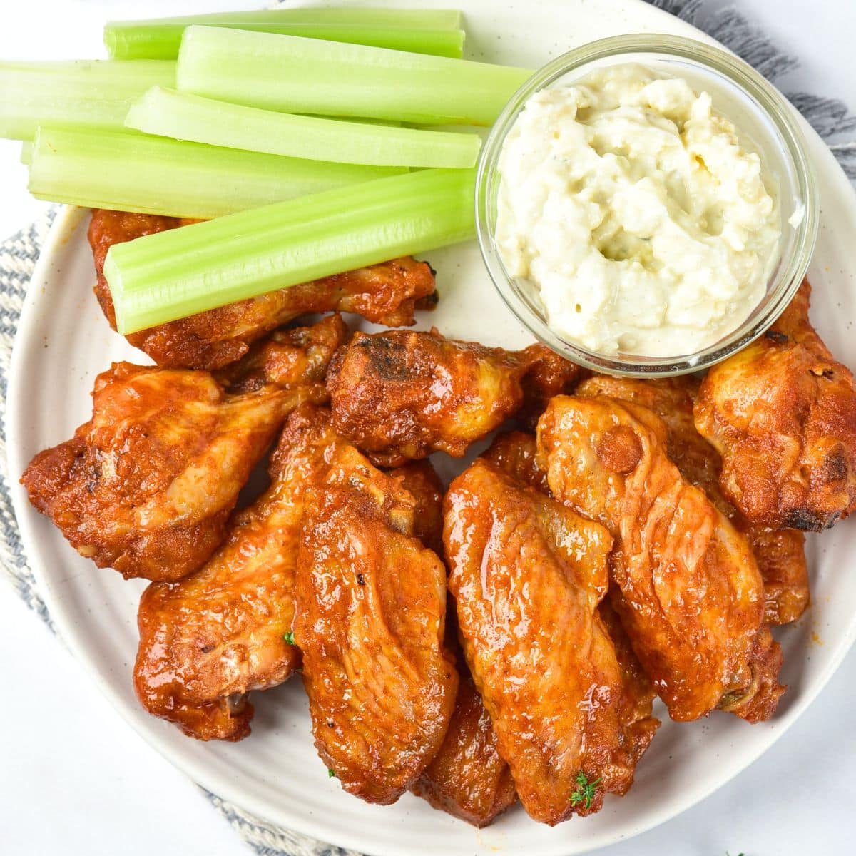 A plate of buffalo wings, celery sticks and ranch dressing.