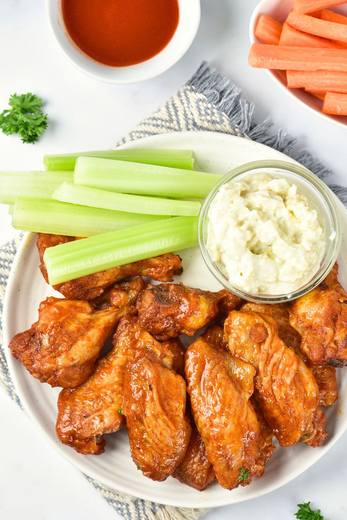 Top down view of a plate of gluten-free buffalo wings and celery sticks