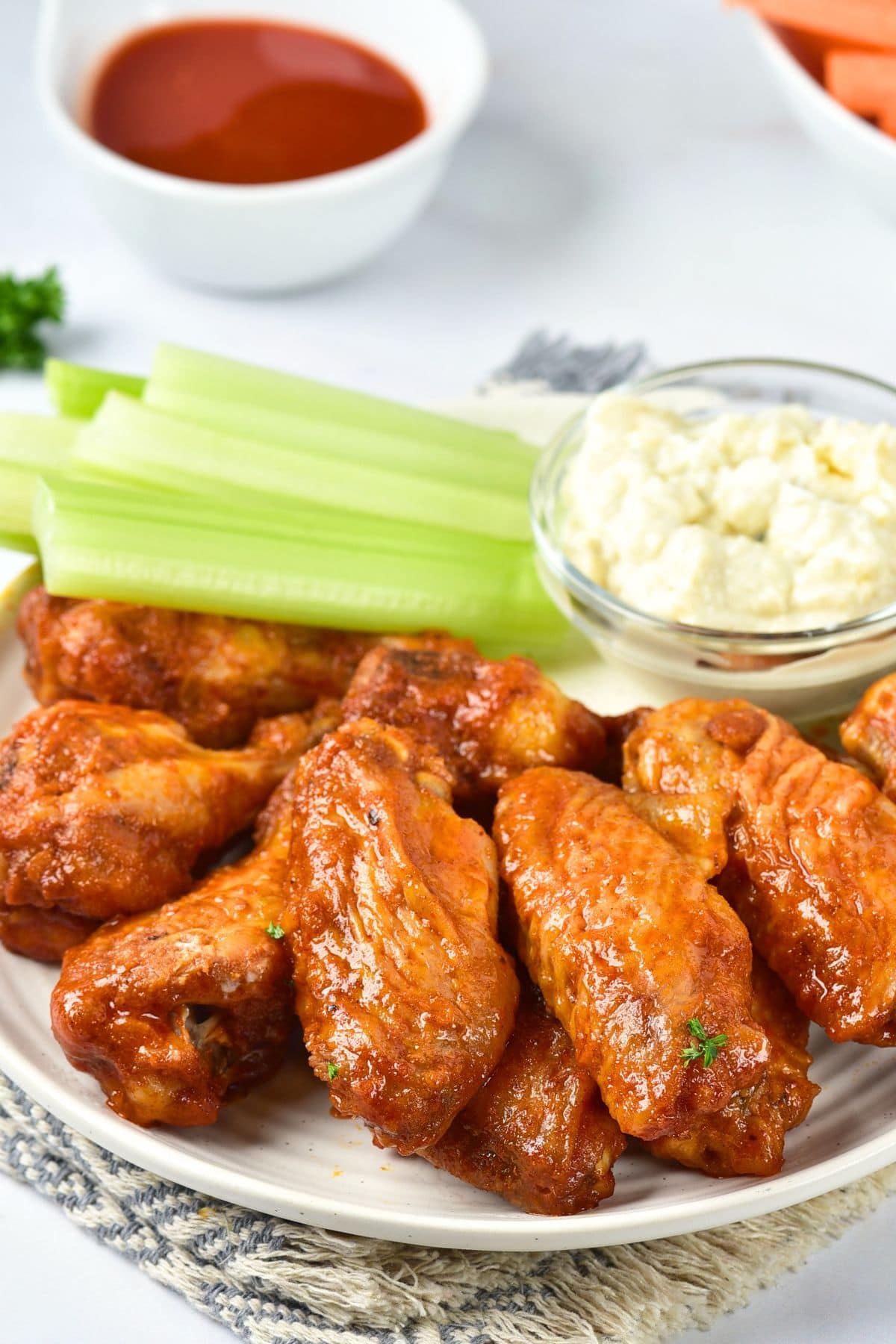 Up close view of a plate of chicken wings tossed in sauce.