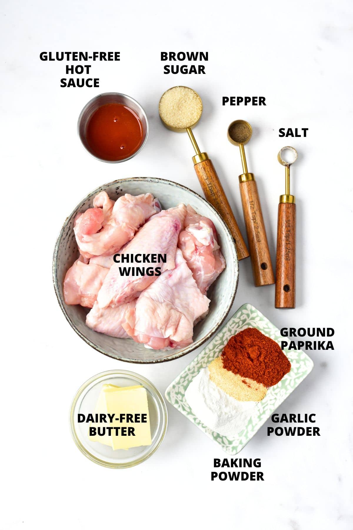 Ingredients for gluten-free buffalo wings recipe laid out on white board.