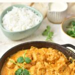 A skillet of butter chicken and a bowl of rice