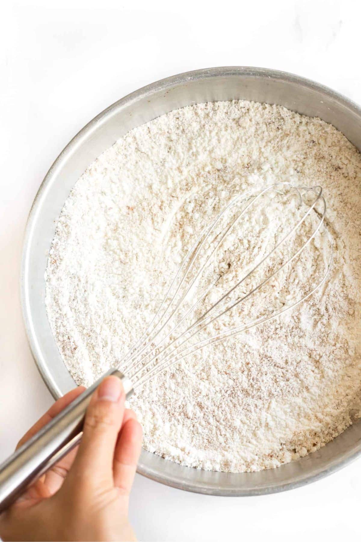 Whisking dry ingredients in metal bowl.