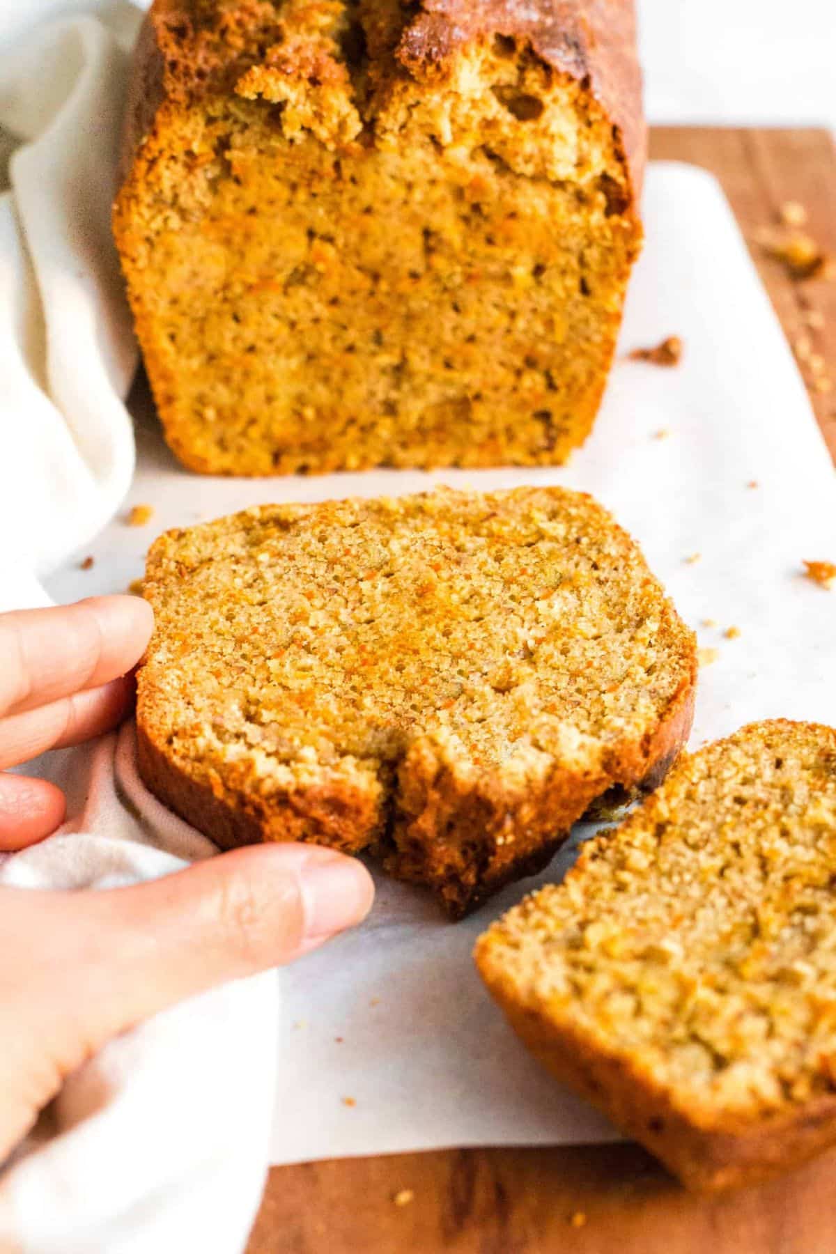 Hand reaching for a slice of gluten-free carrot cake bread.