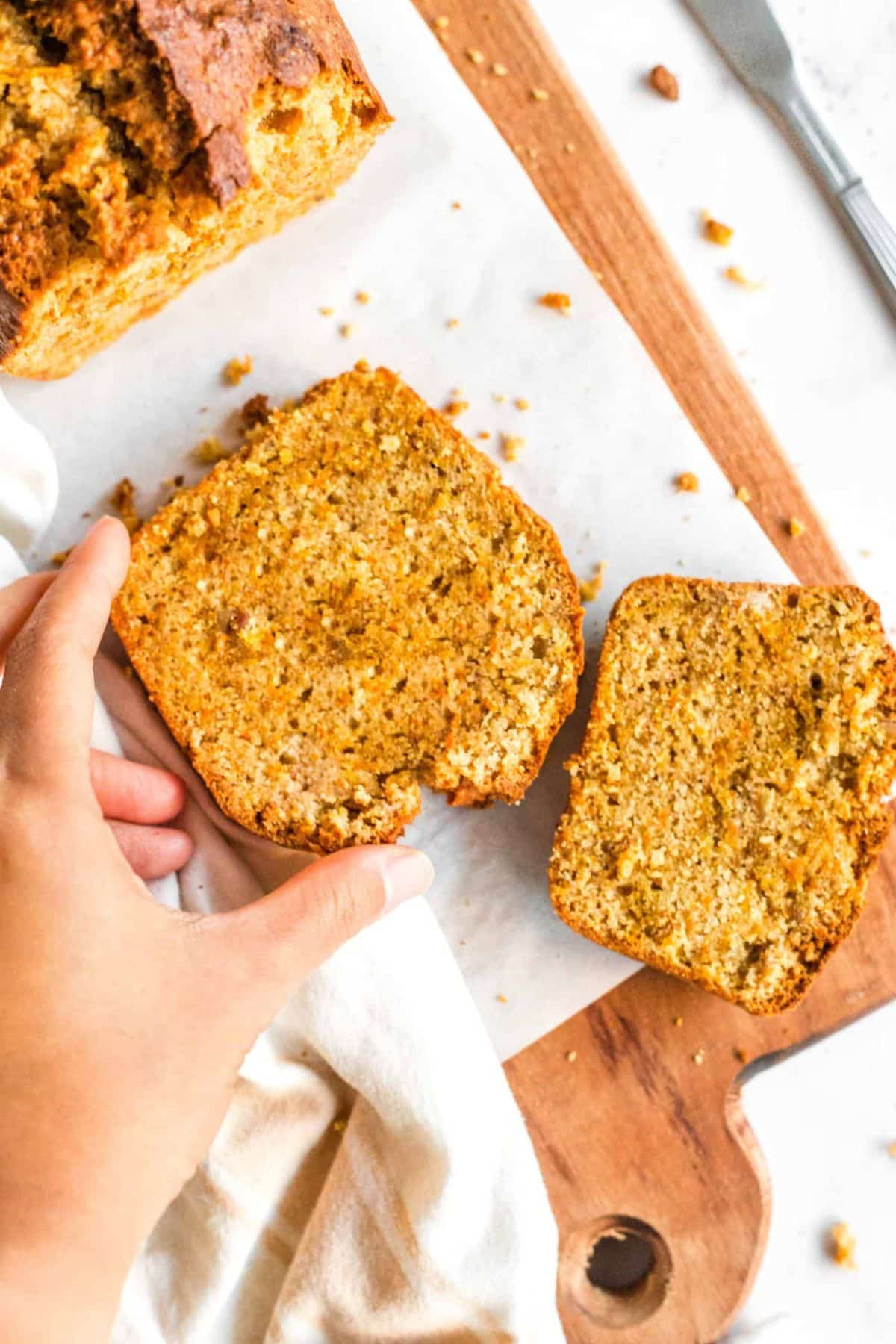 Hand reaching for a slice of carrot cake bread.