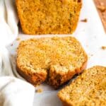 Half-sliced loaf of carrot bread on parchment paper.