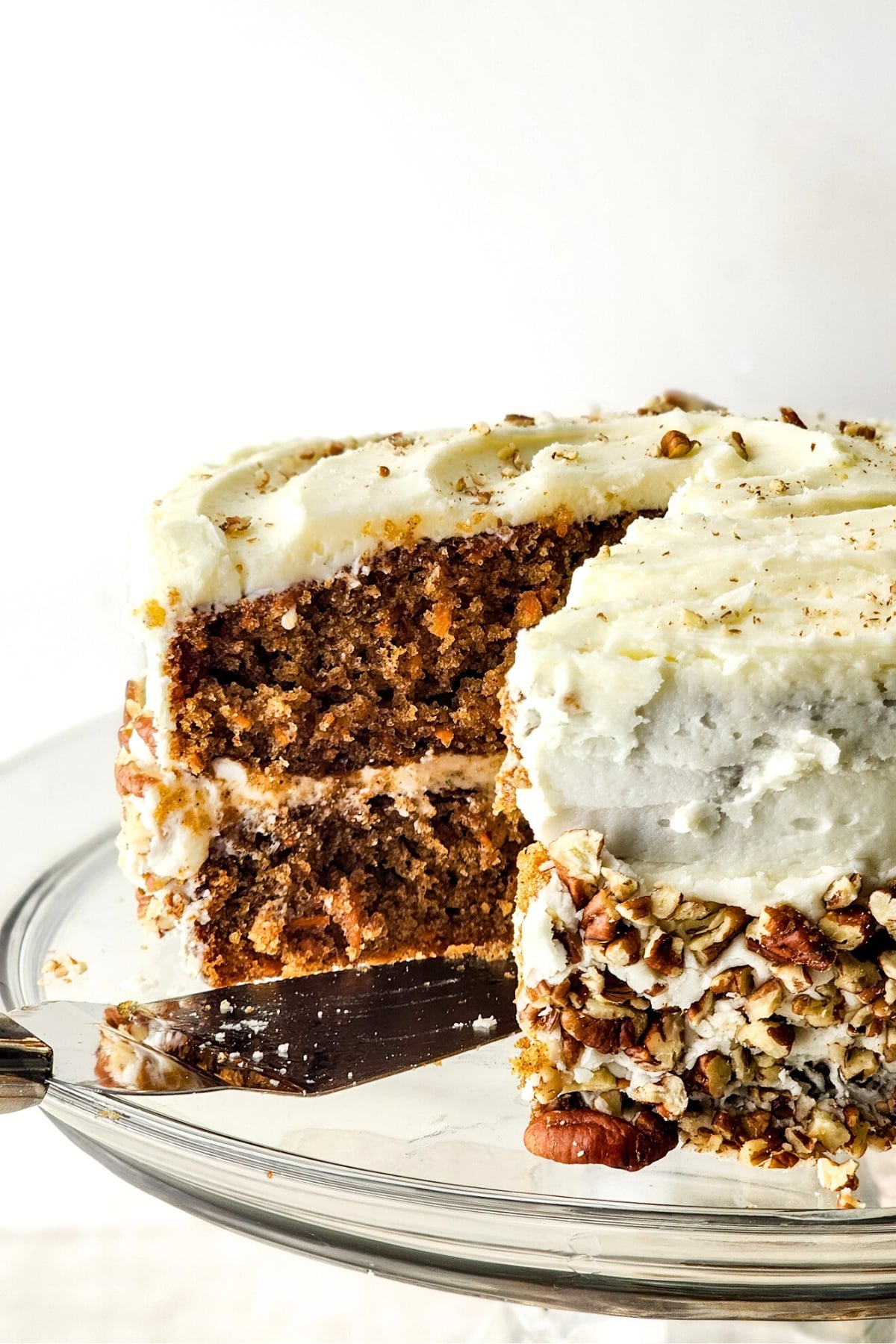 A half-sliced gluten-free dairy-free carrot cake on cake stand.