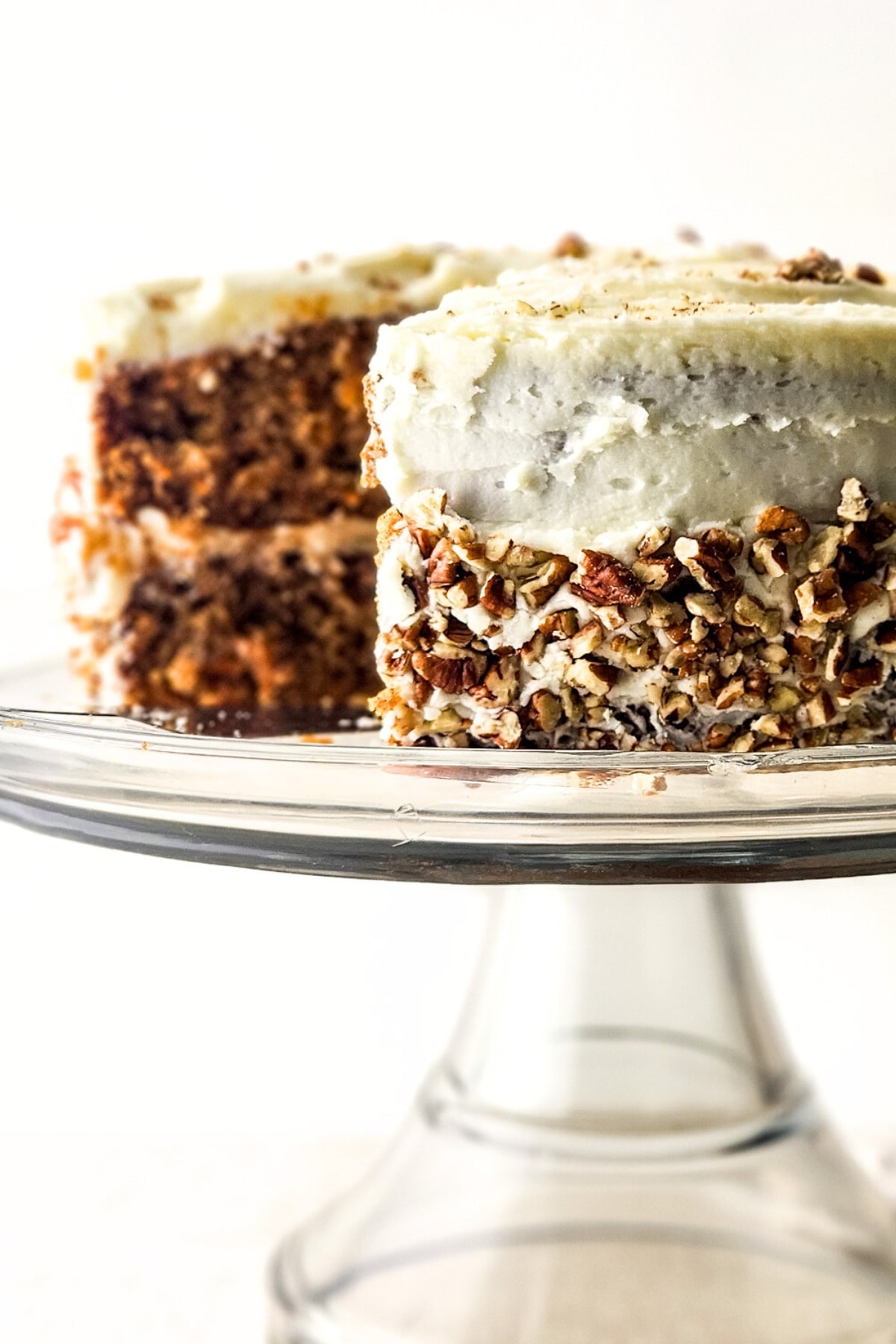Half-eaten carrot cake on cake stand.
