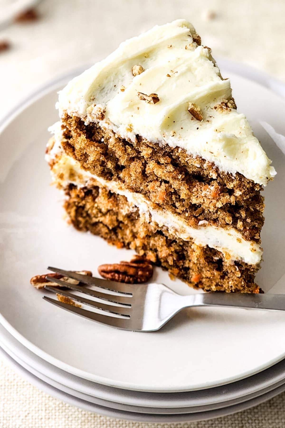 A slice of moist gluten-free carrot cake and a fork on white plate.