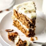 Half-eaten carrot cake slice on white plates.