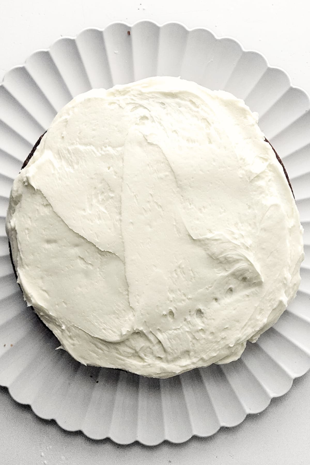Cream cheese frosting spread over carrot cake.