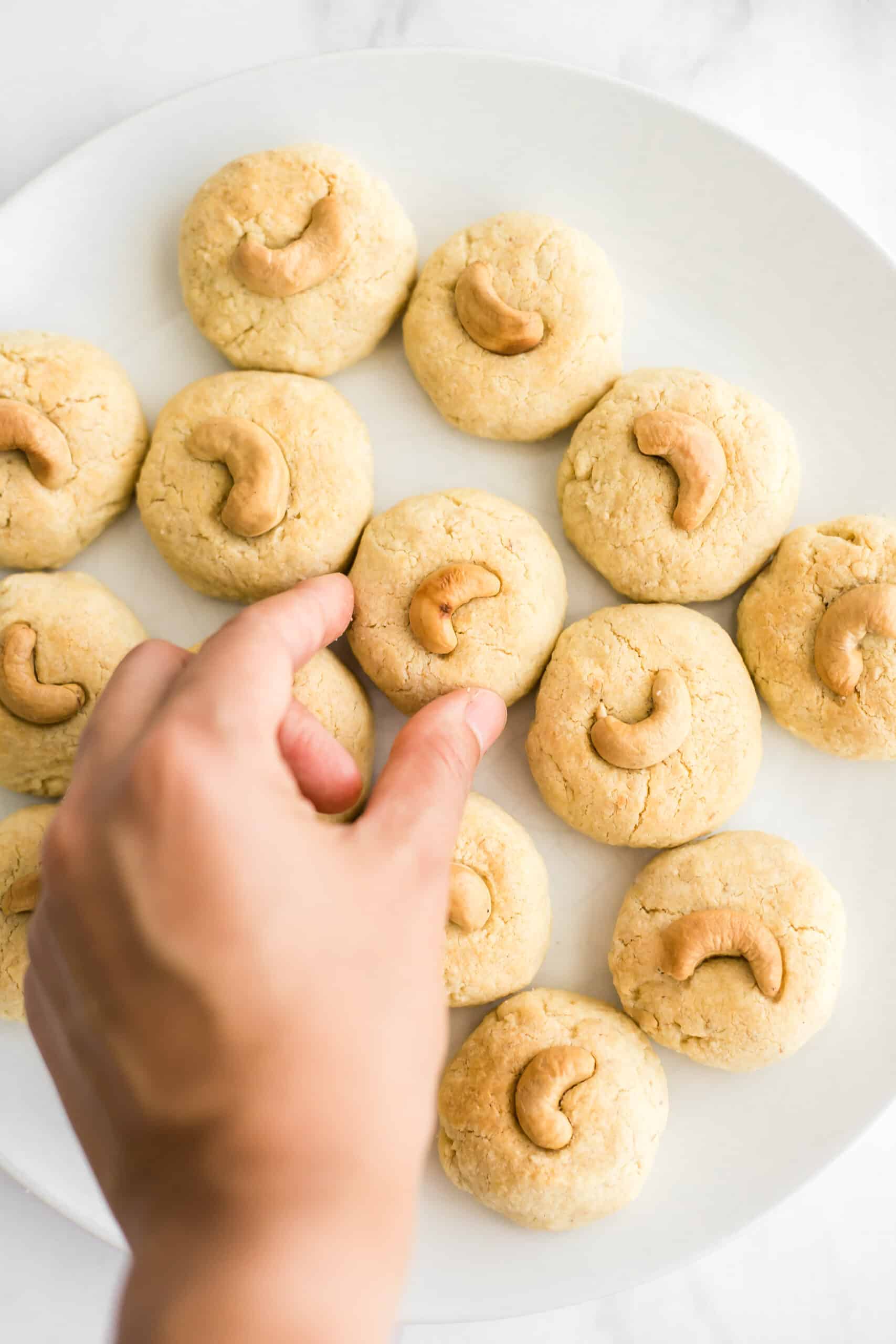 Hand reaching for a gluten-free cashew nut cookie.