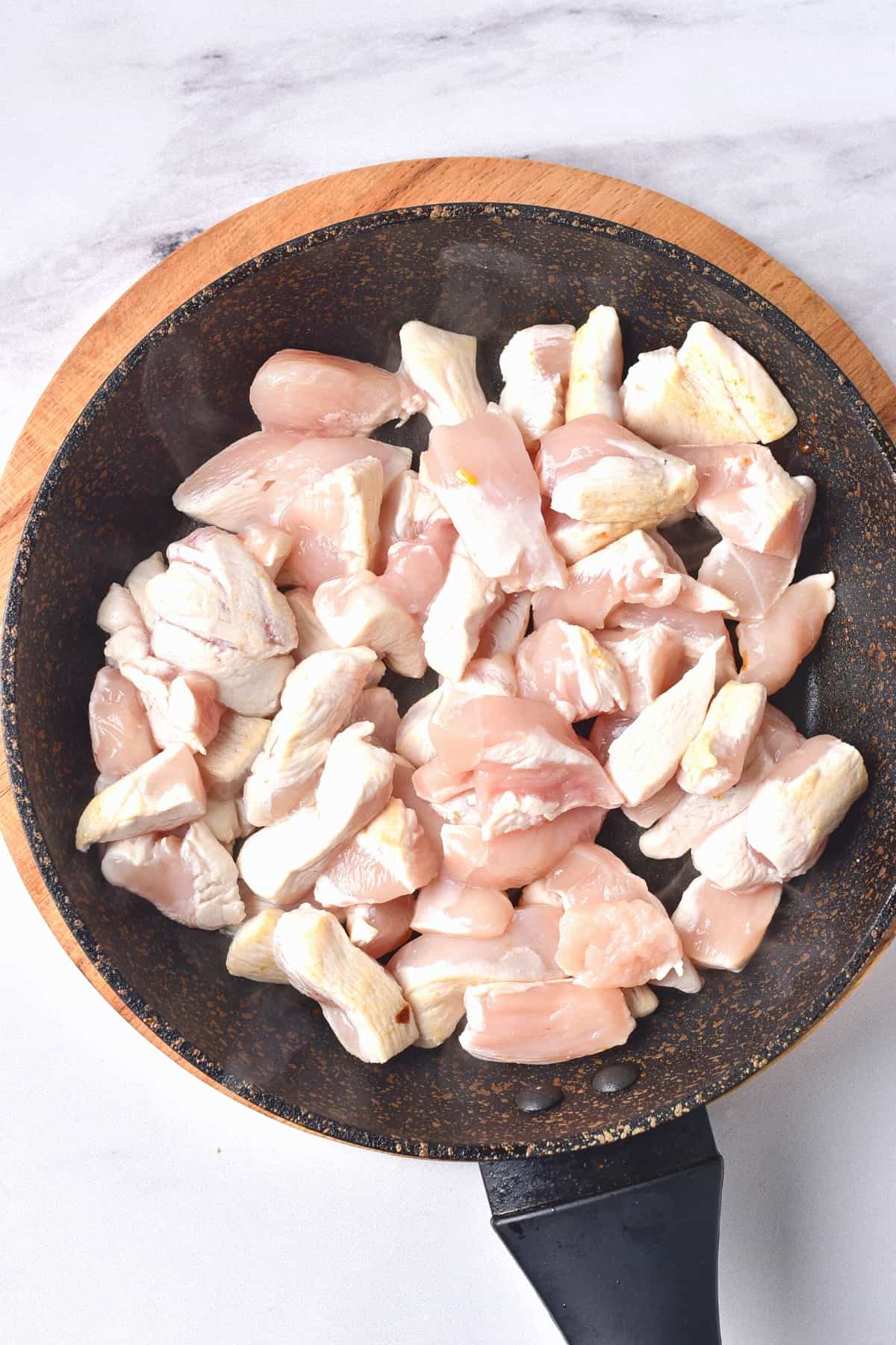 Cooking pieces of chicken in a skillet.