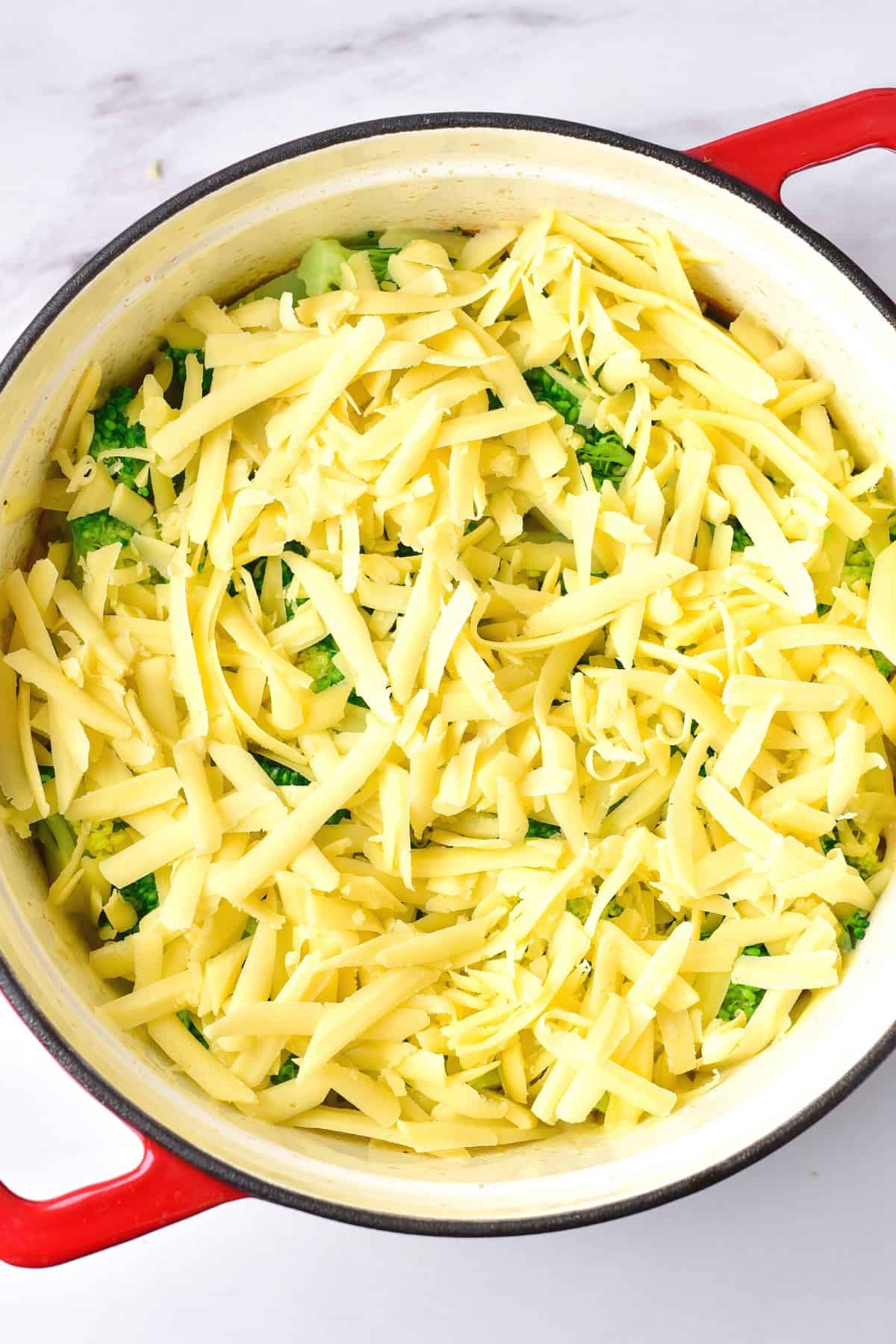 A dutch oven filled with cheese and broccoli.