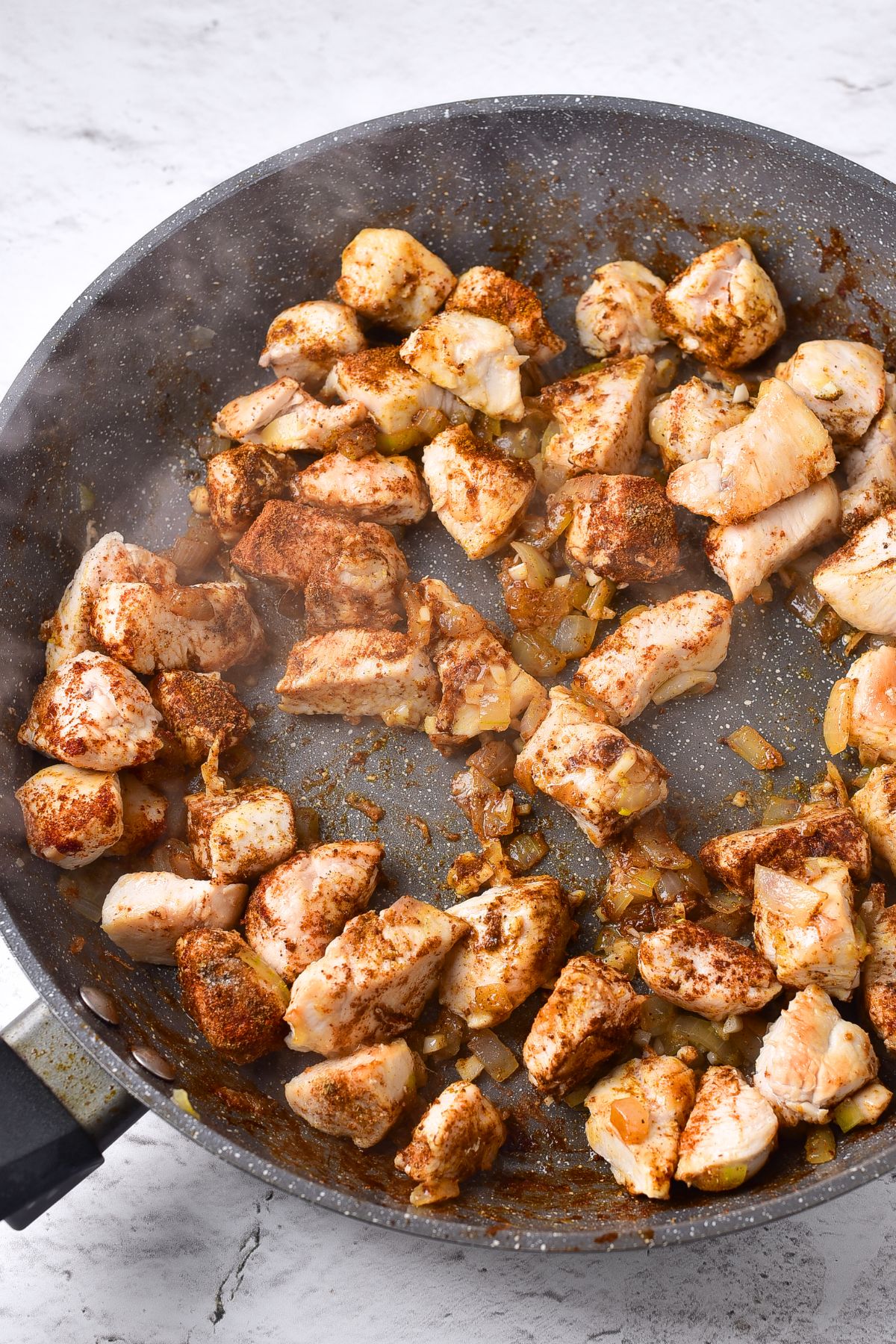 Cooking cubed chicken, onions, garlic and ginger and spices in skillet.