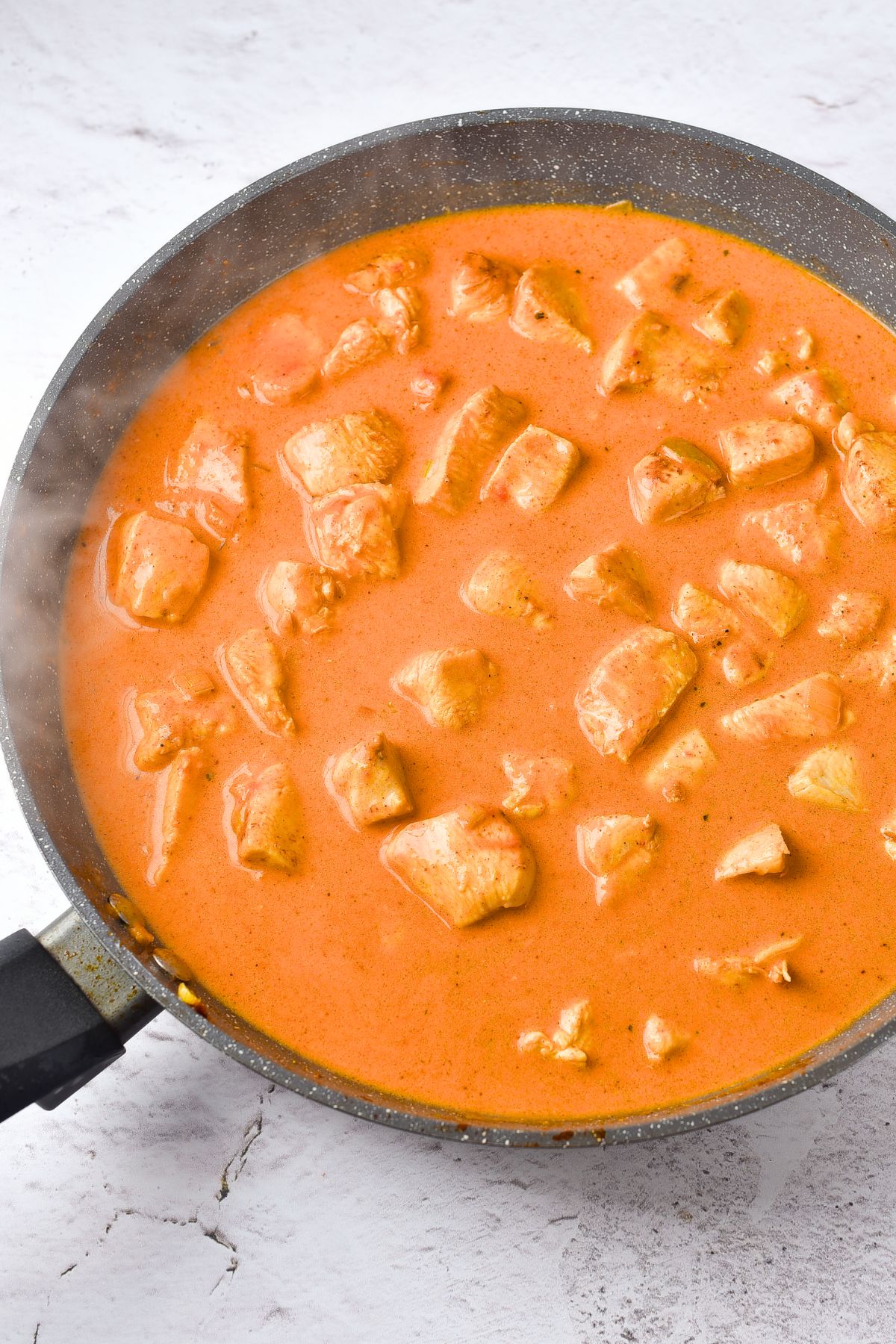 Top down view of a skillet with gluten-free curry chicken.