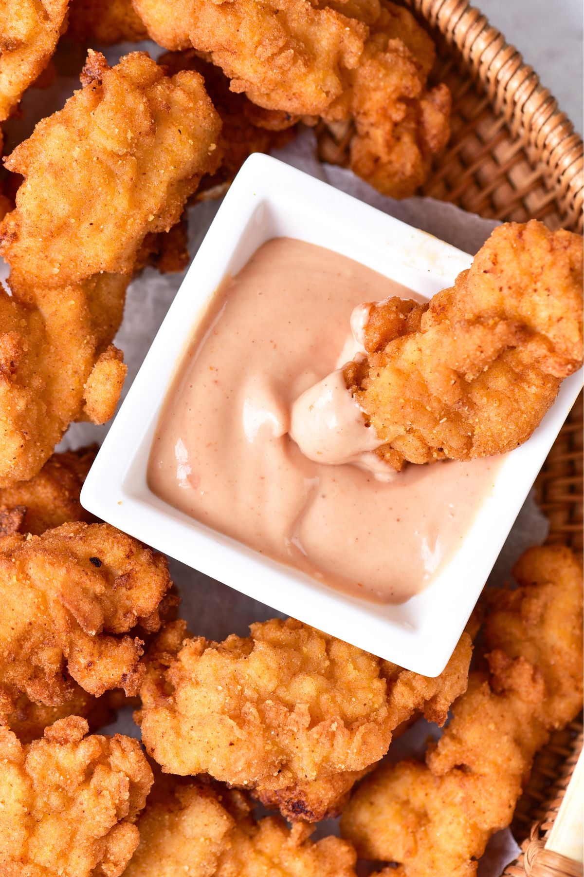 Up close shot of a chicken strip being dipped in sauce.