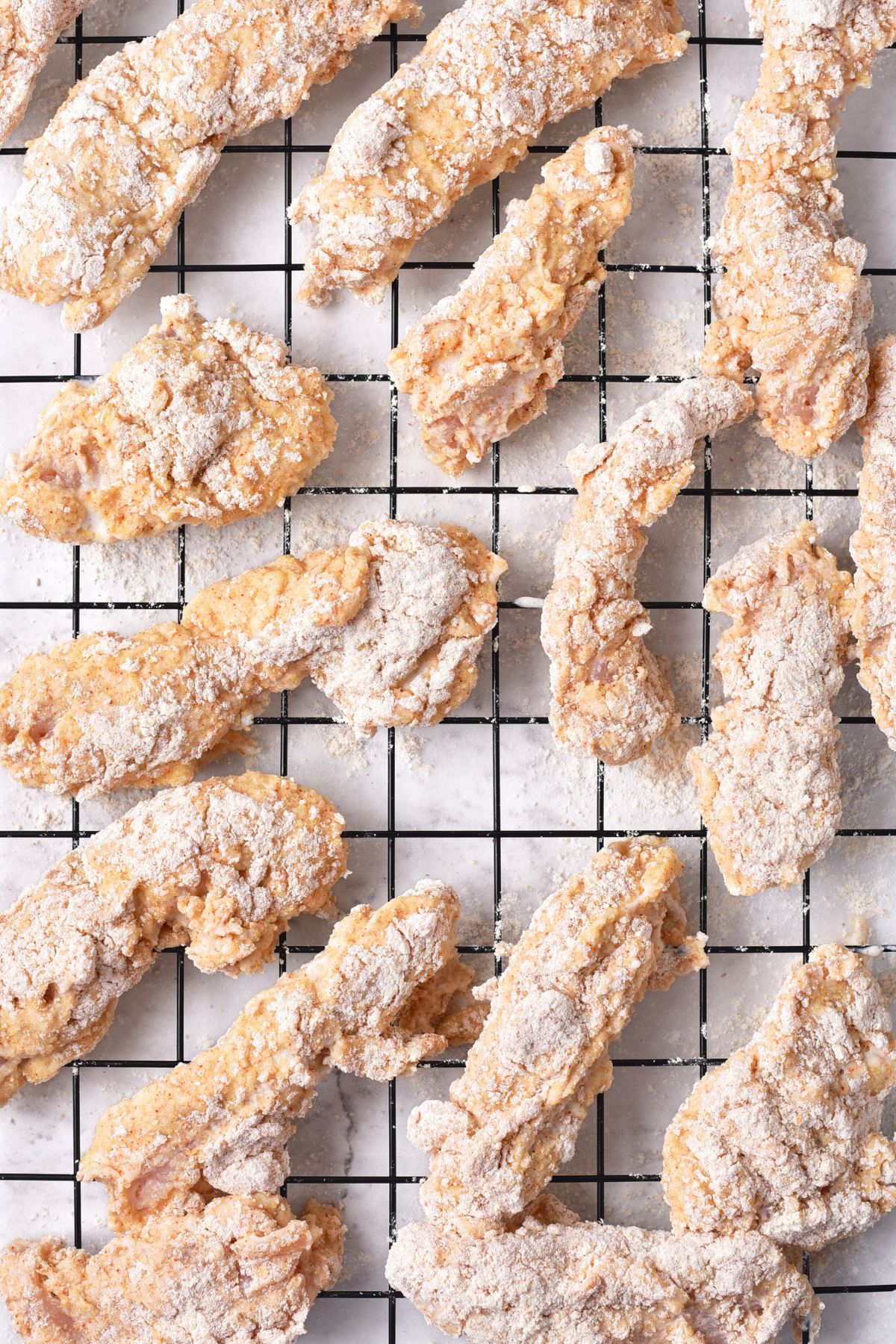 Uncooked chicken fingers on wire rack