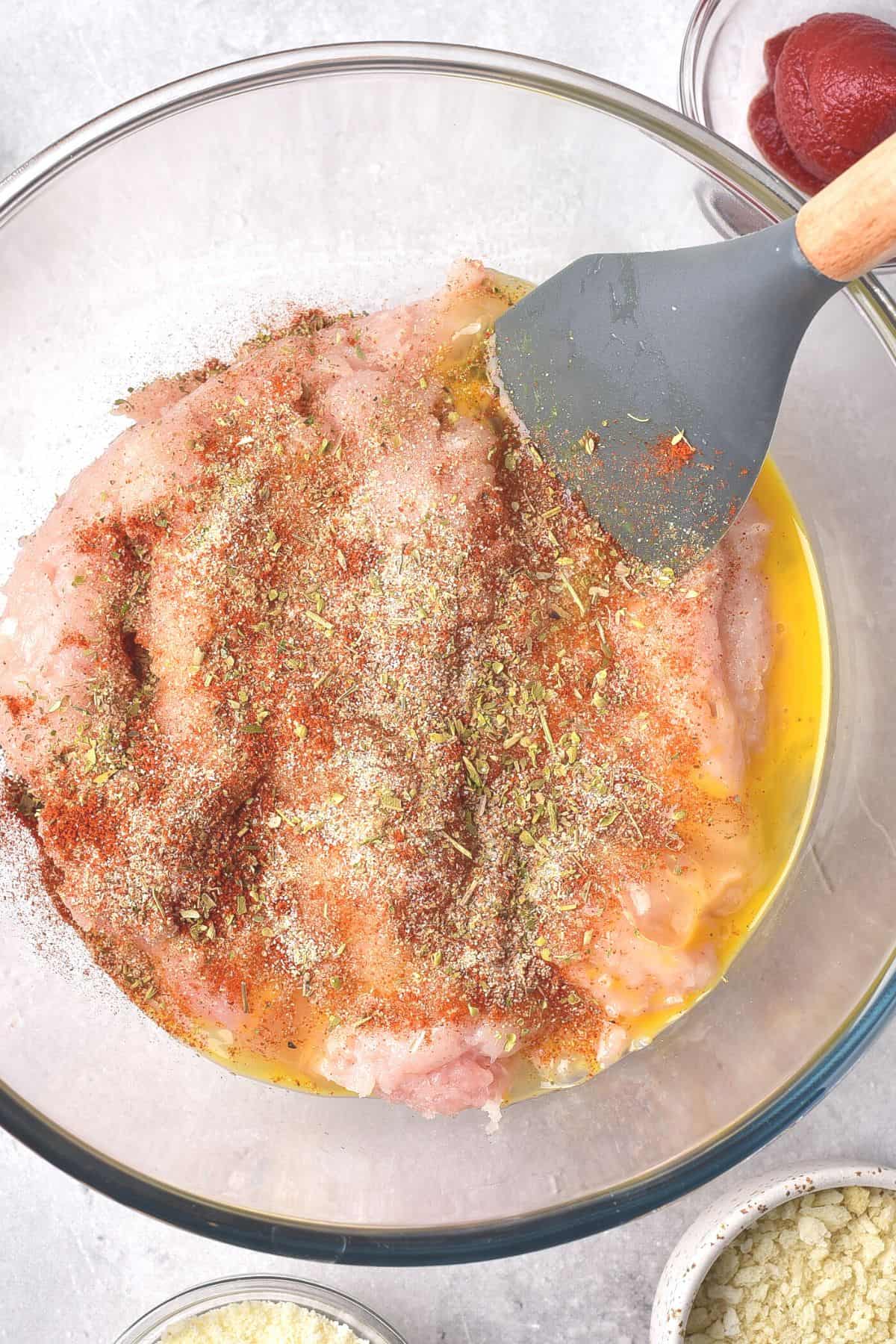 Mixing ground chicken with egg and spices.