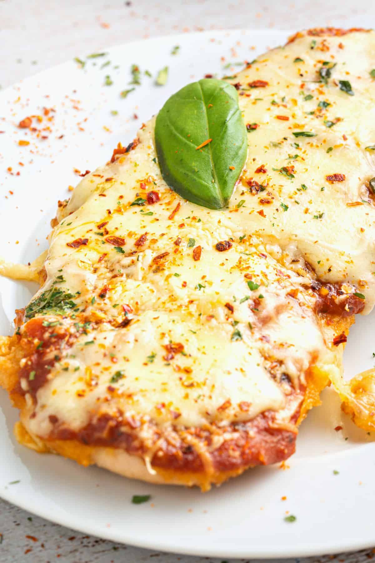 A portion of baked chicken parmesan on a plate. 