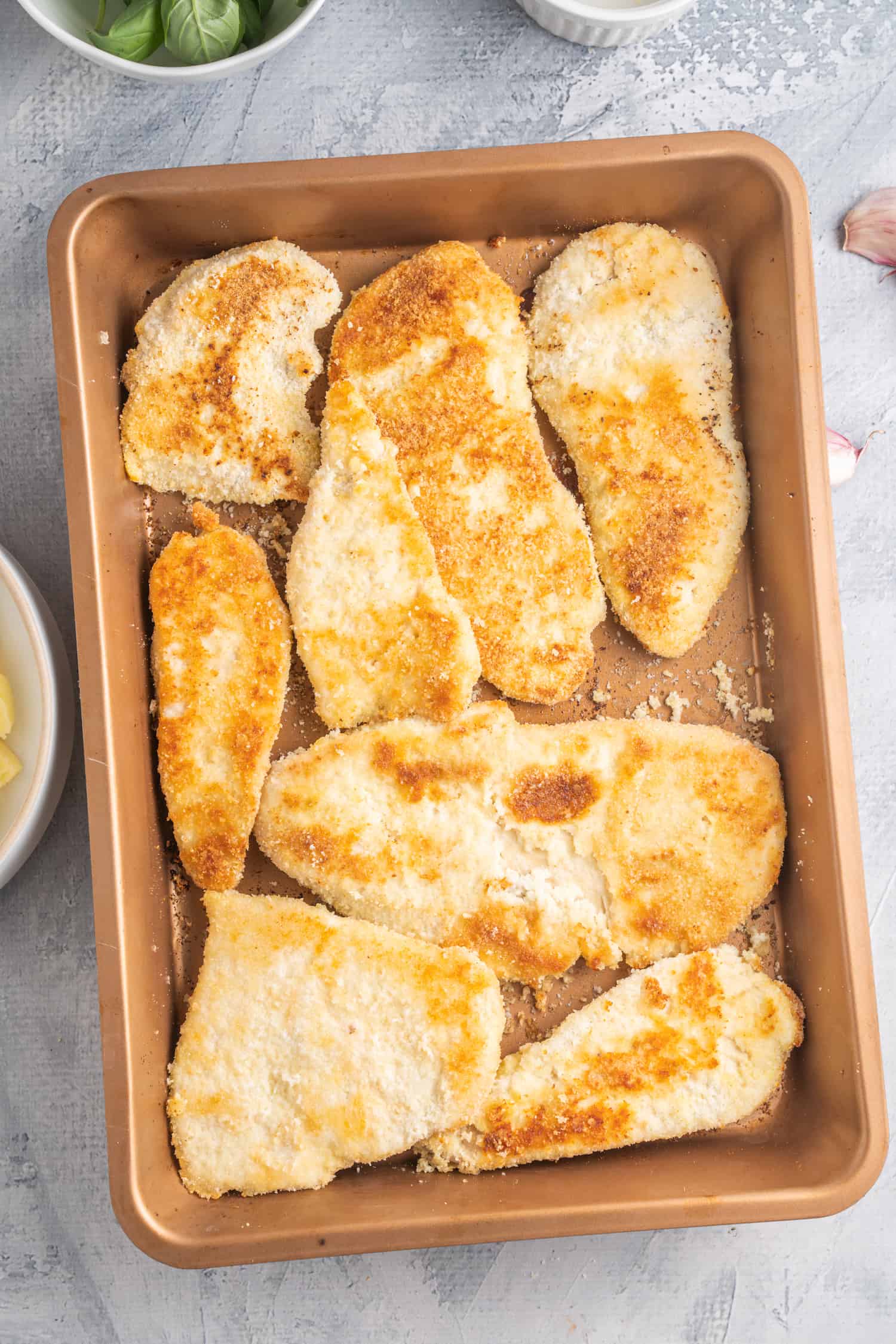 Baked chicken cutlets on a baking tray.