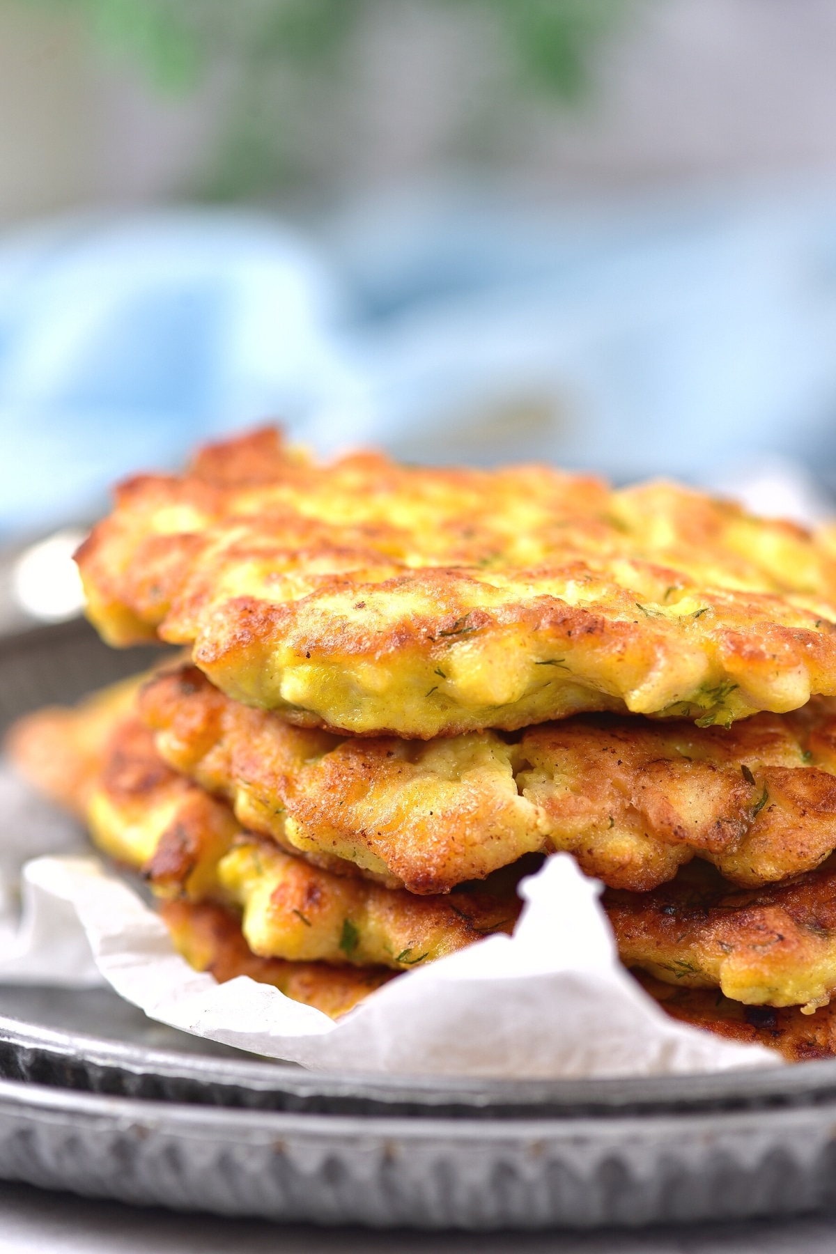 A stack of gf chicken patties on parchment-lined plate.