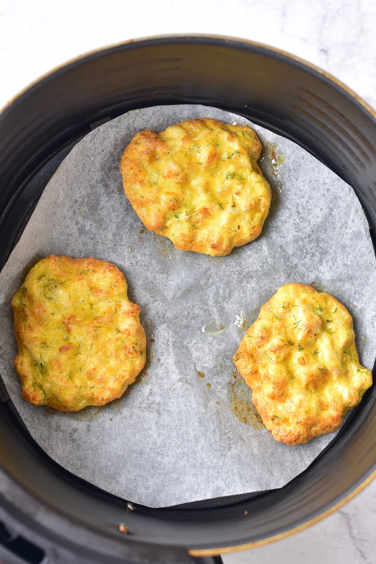 Air fried chicken patties in air fryer basket.
