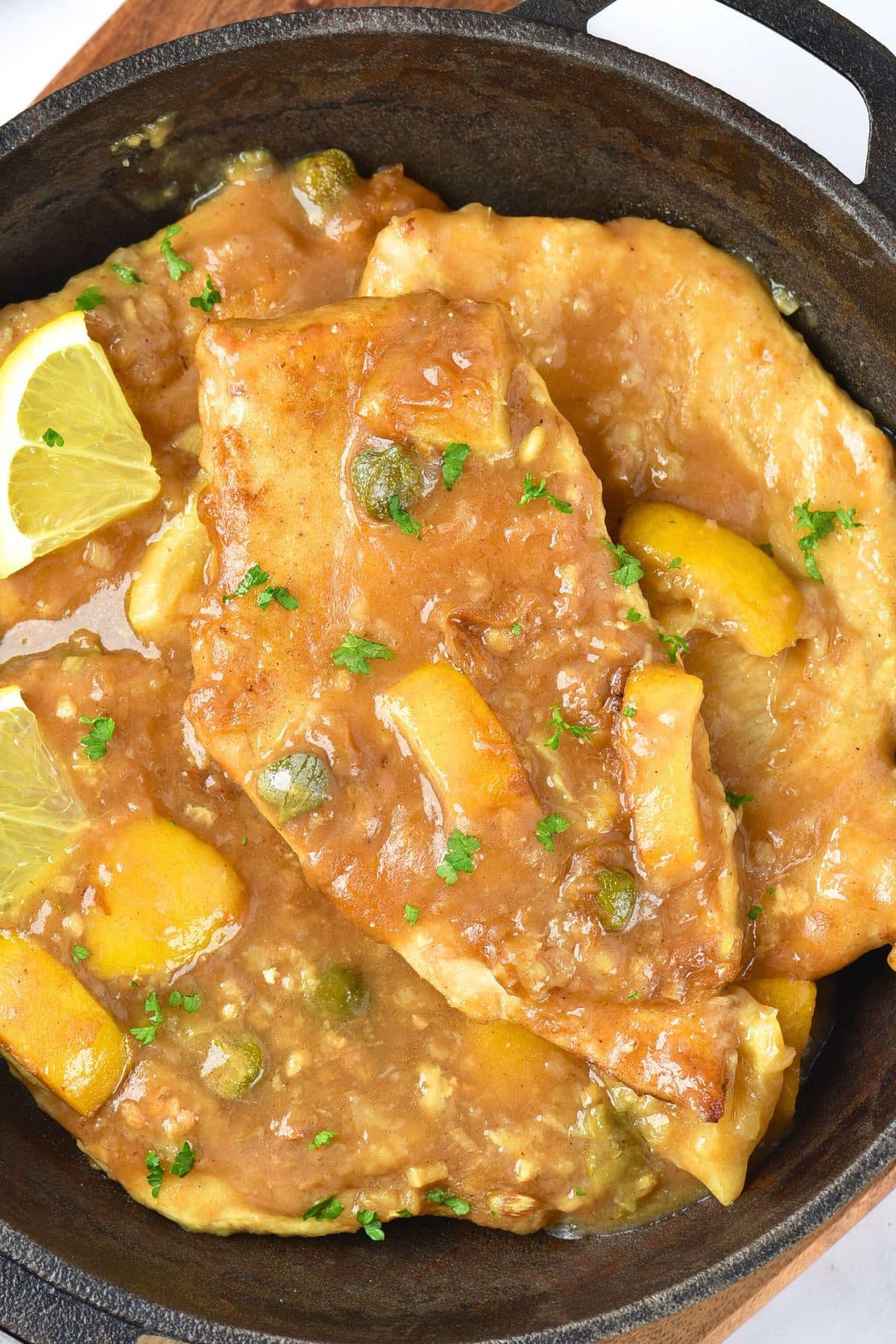 A skillet with lemon chicken piccata.