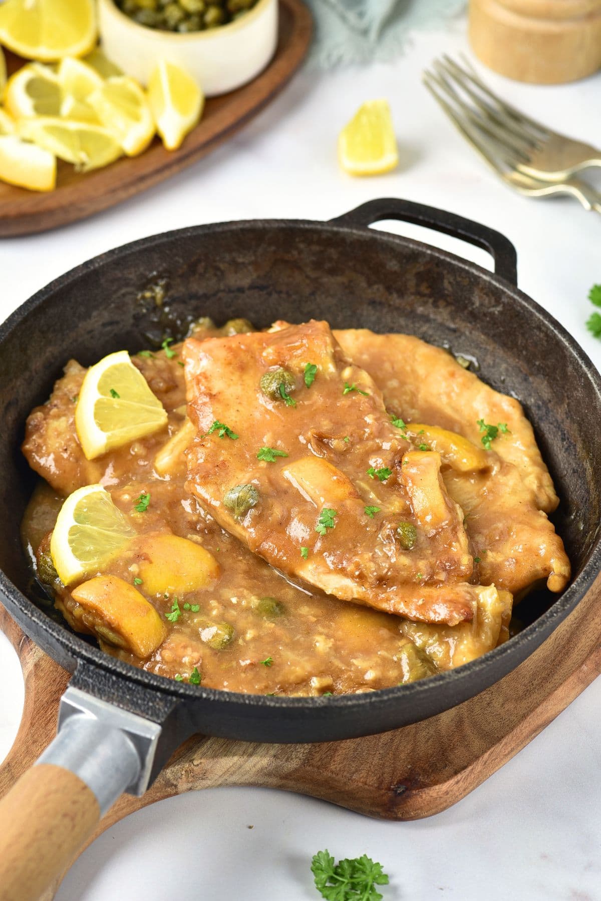 Chicken piccata with slices of lemon in a skillet