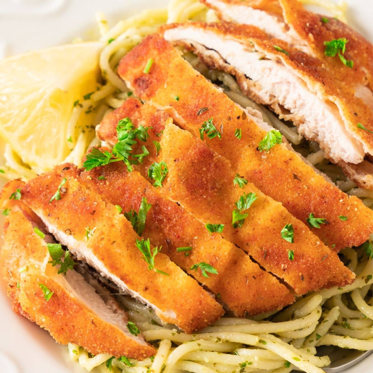 Sliced gluten-free chicken schnitzel on top of spaghetti