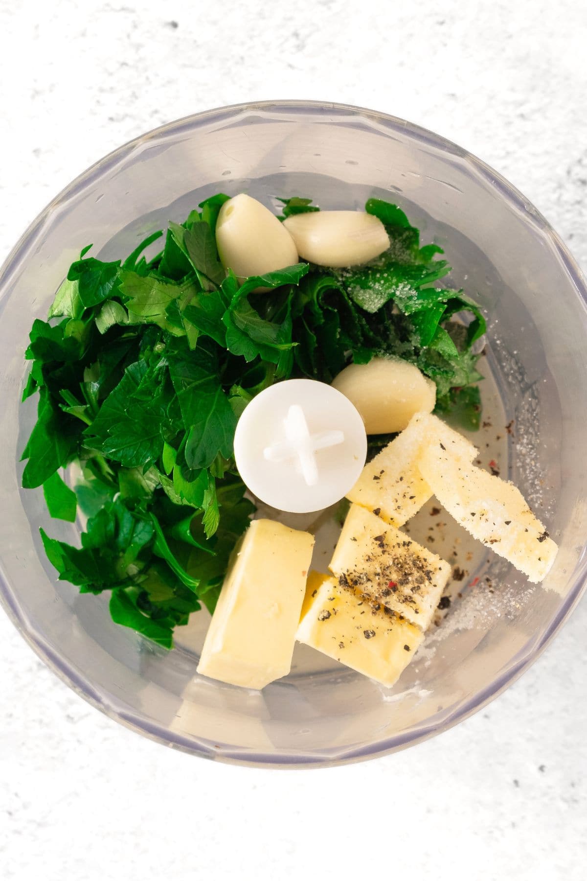 Parsley, butter, garlic cloves and pepper in food processor.