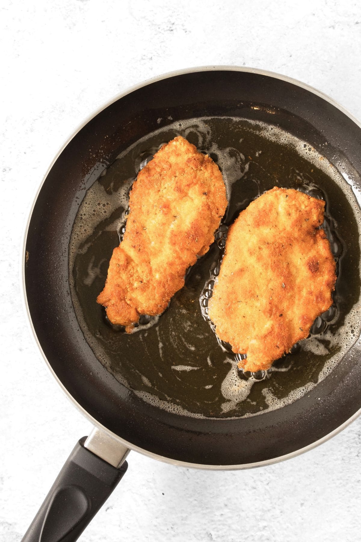 Pan-frying breaded chicken schnitzel in skillet