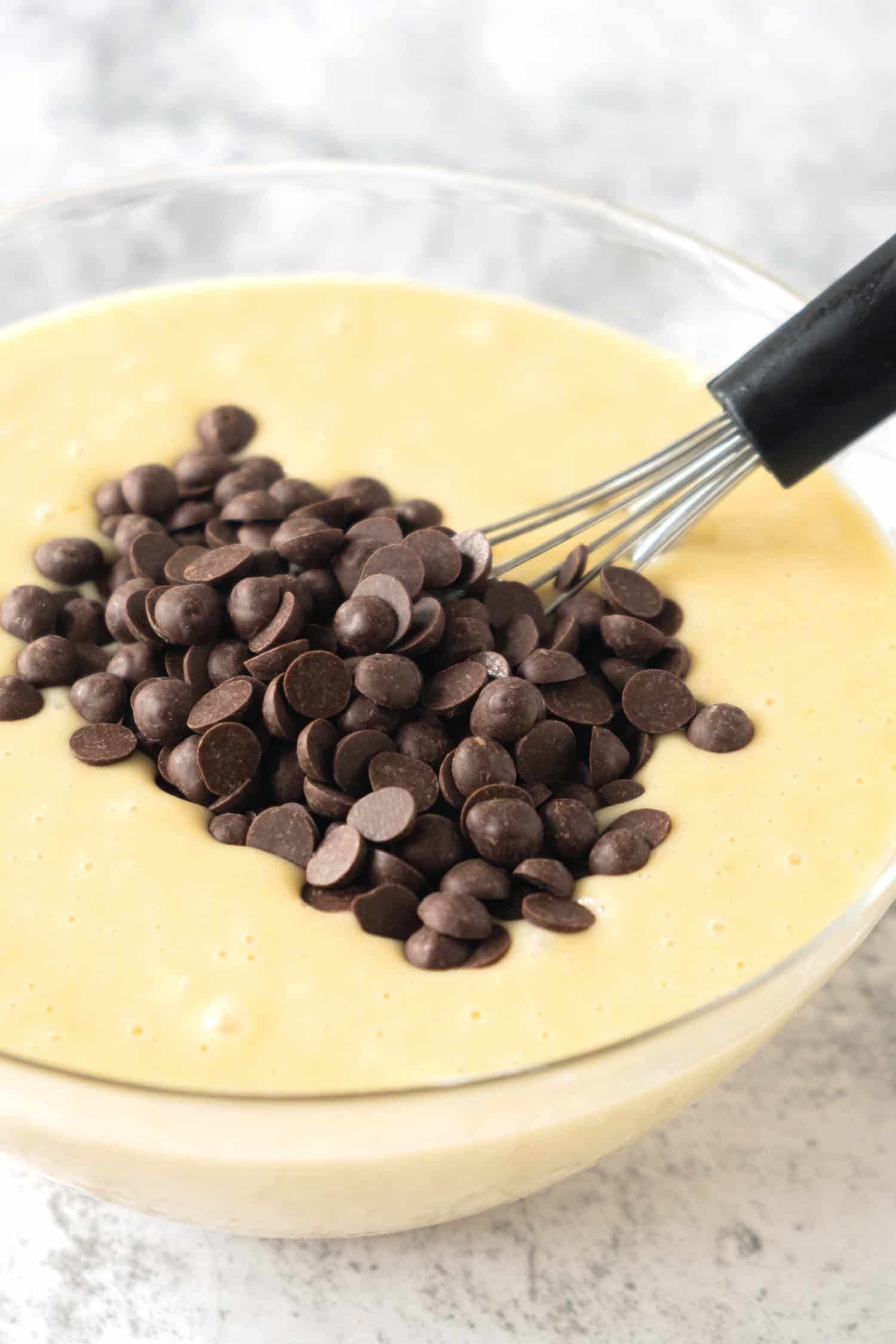 Chocolate chips on top of a bowl of muffin batter.