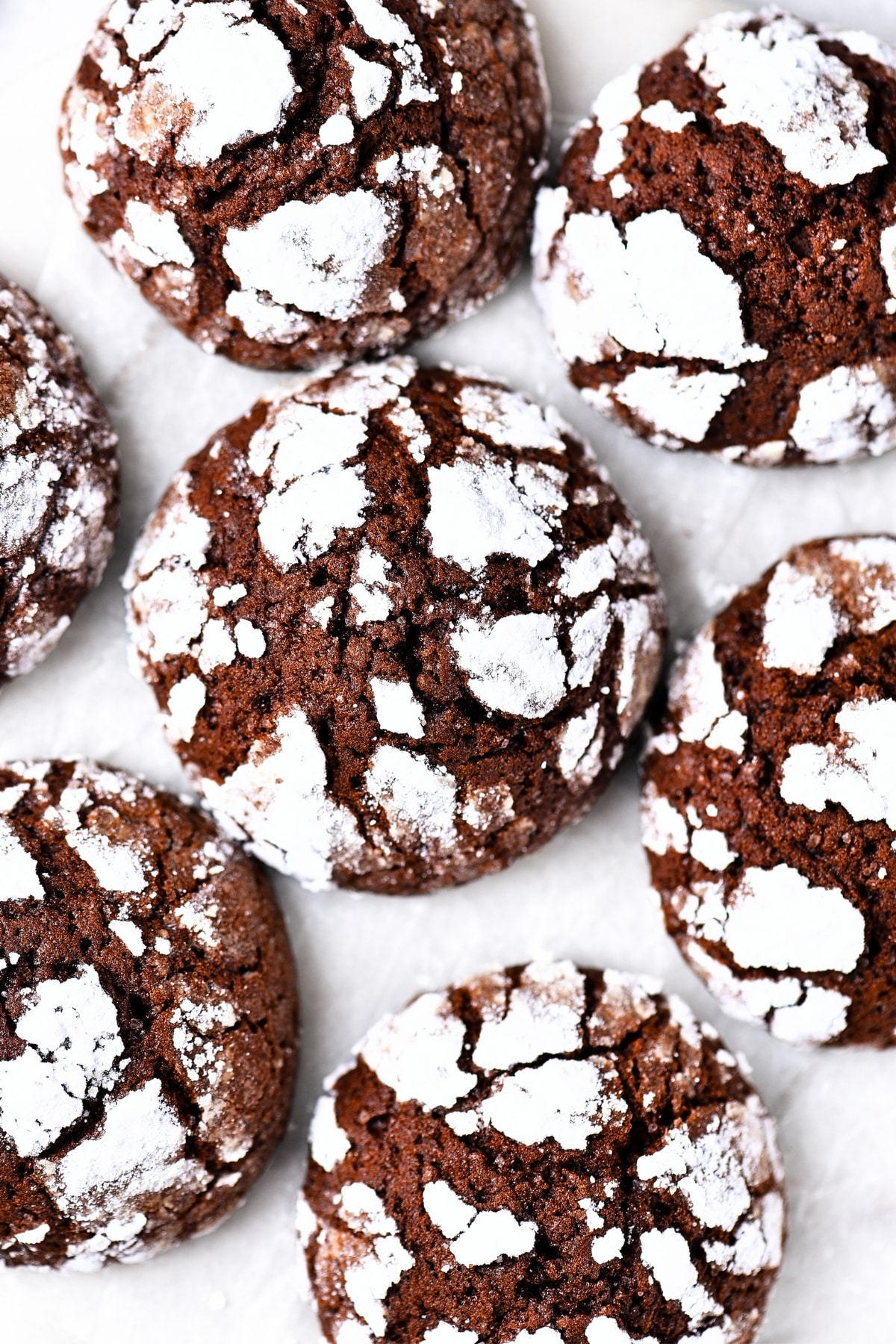 Top down view of gluten-free chocolate crinkle cookies on parchment paper.