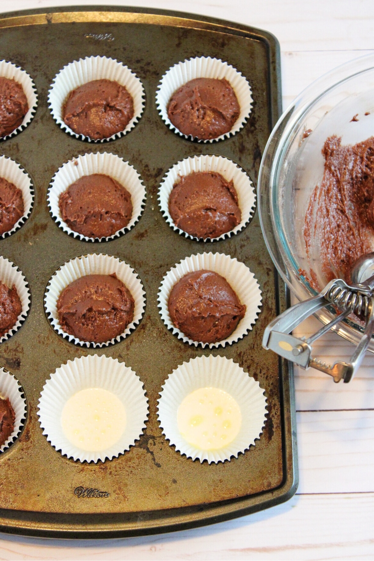 Transferring chocolate cupcake batter to cupcake liners