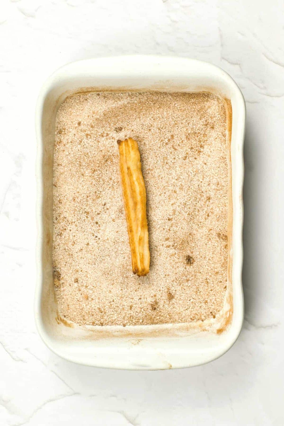 Rolling freshly cooked churro in cinnamon sugar mixture.