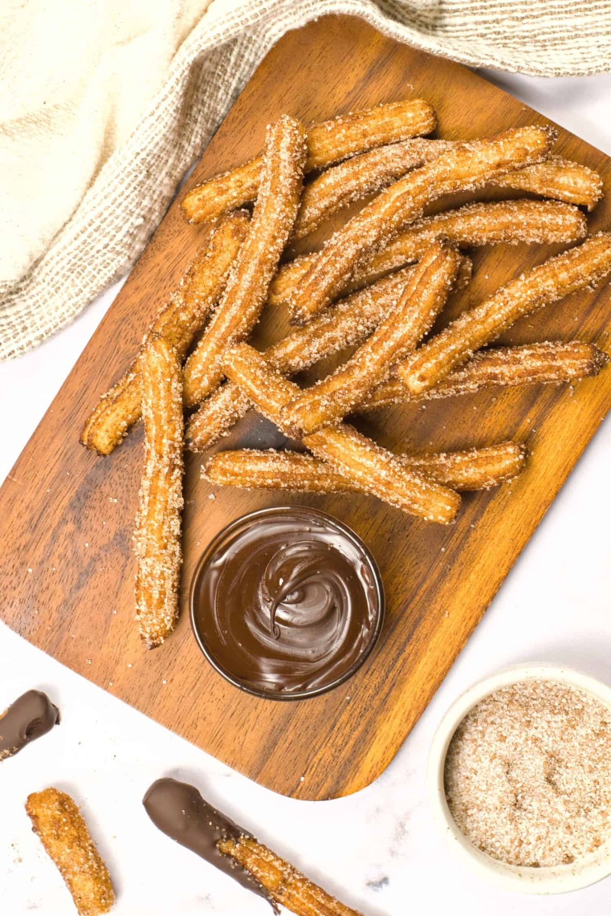 Top down view of homemade churros on wooden board.