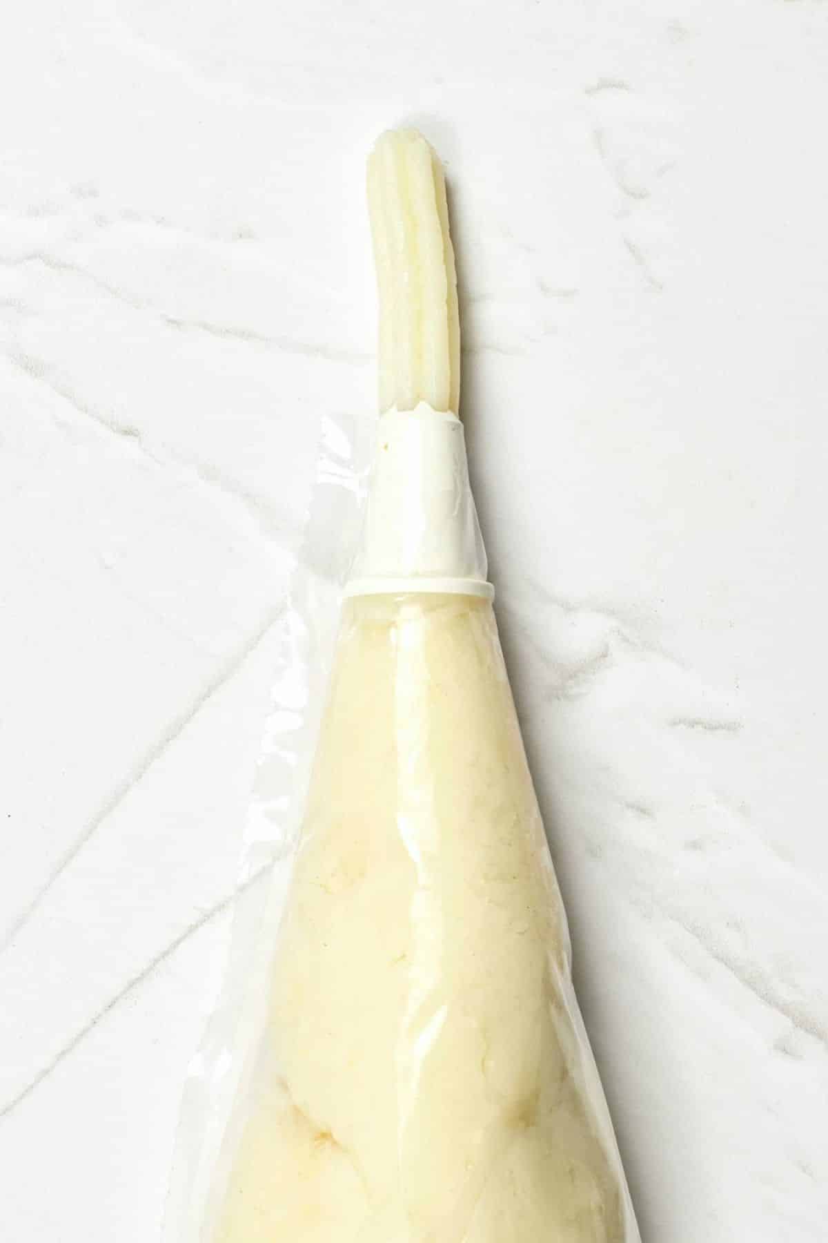 Piping churro dough from a piping bag.