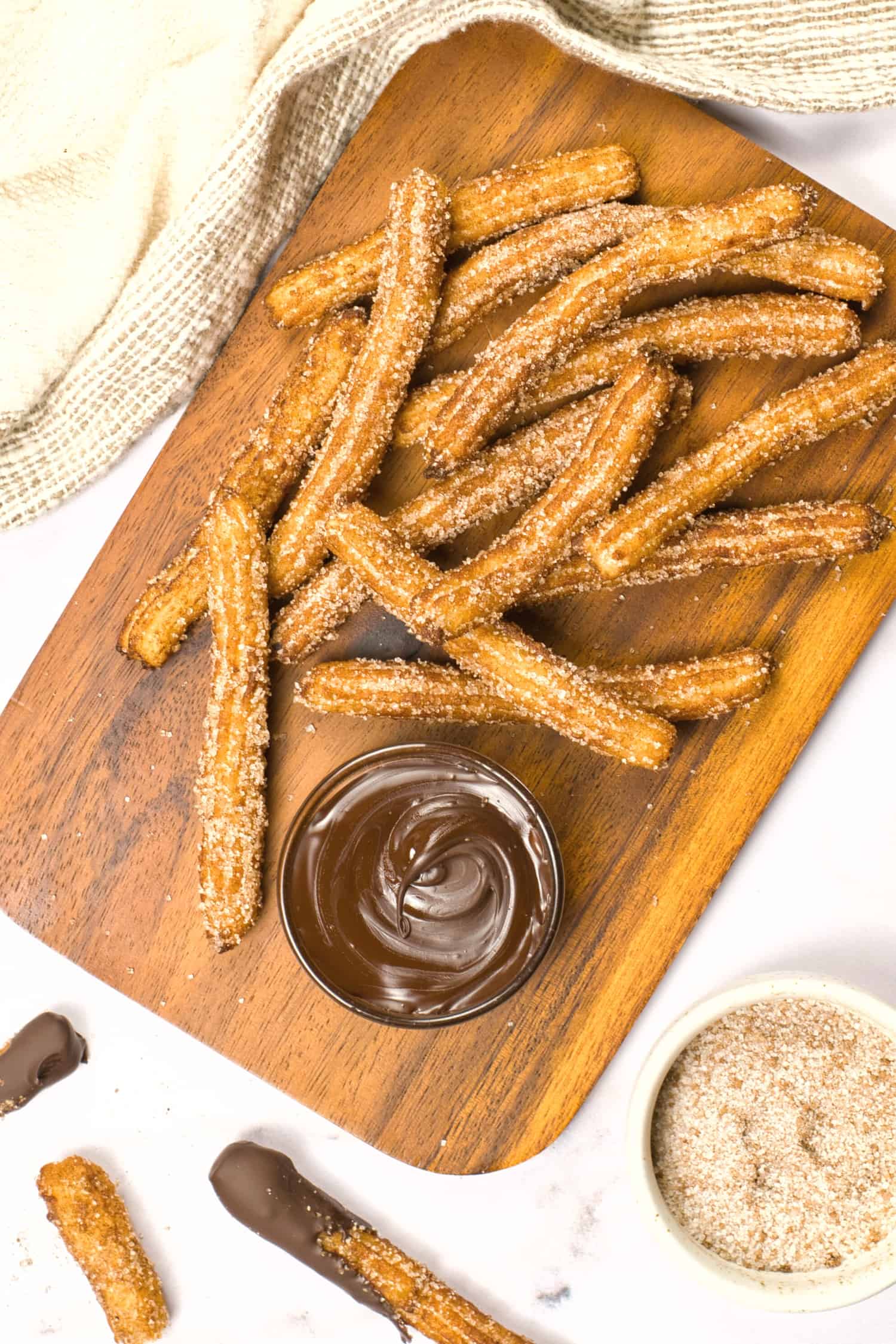 Top down view of a wooden board with gluten free churros and chocolate.
