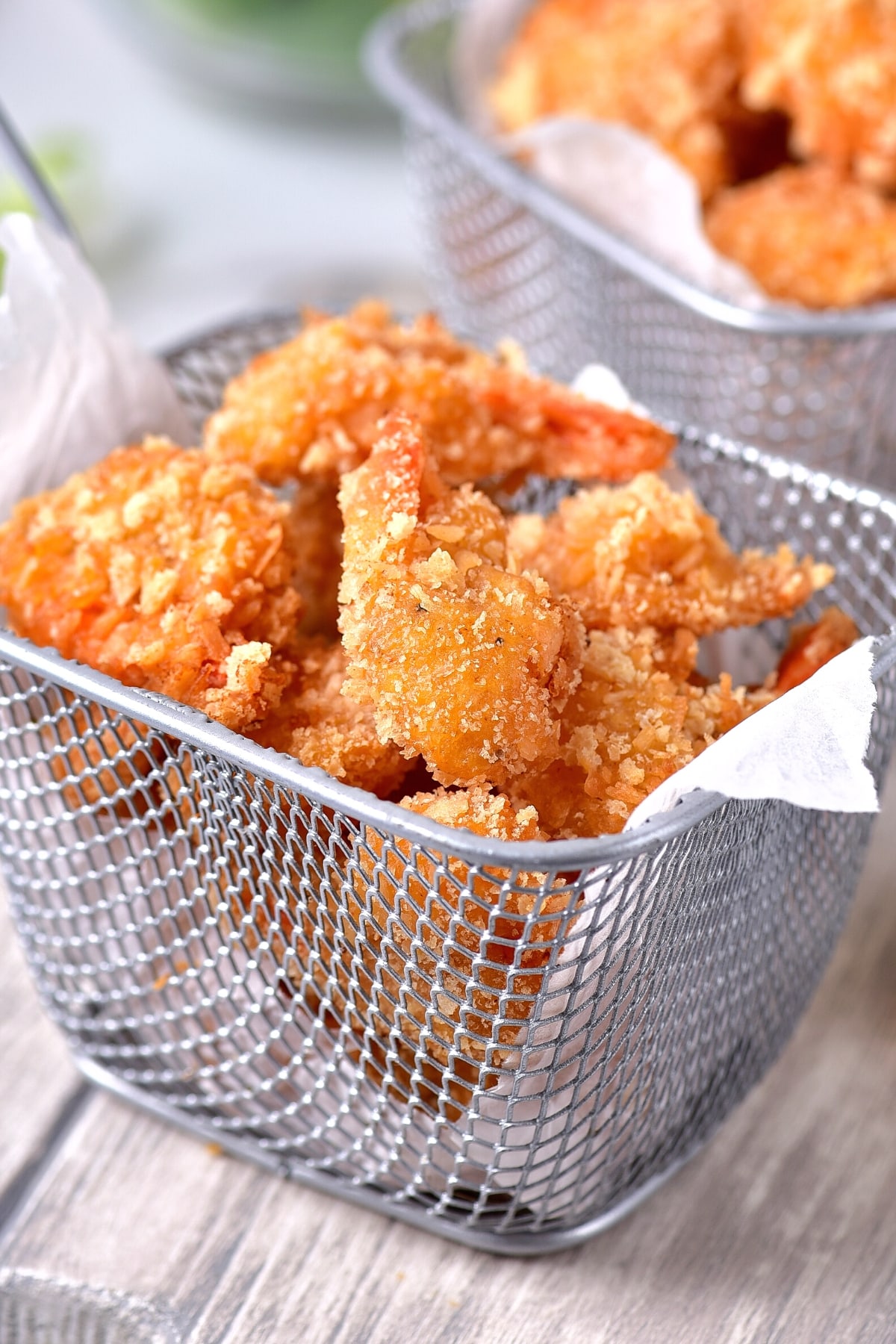 Up close shot of coconut shrimp in metal basket.