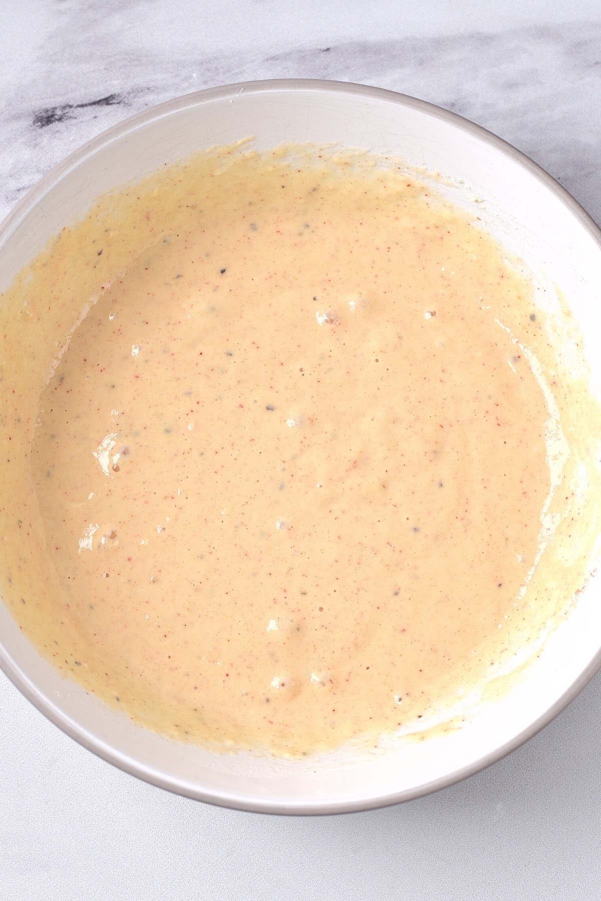 Pale orange batter in white mixing bowl.