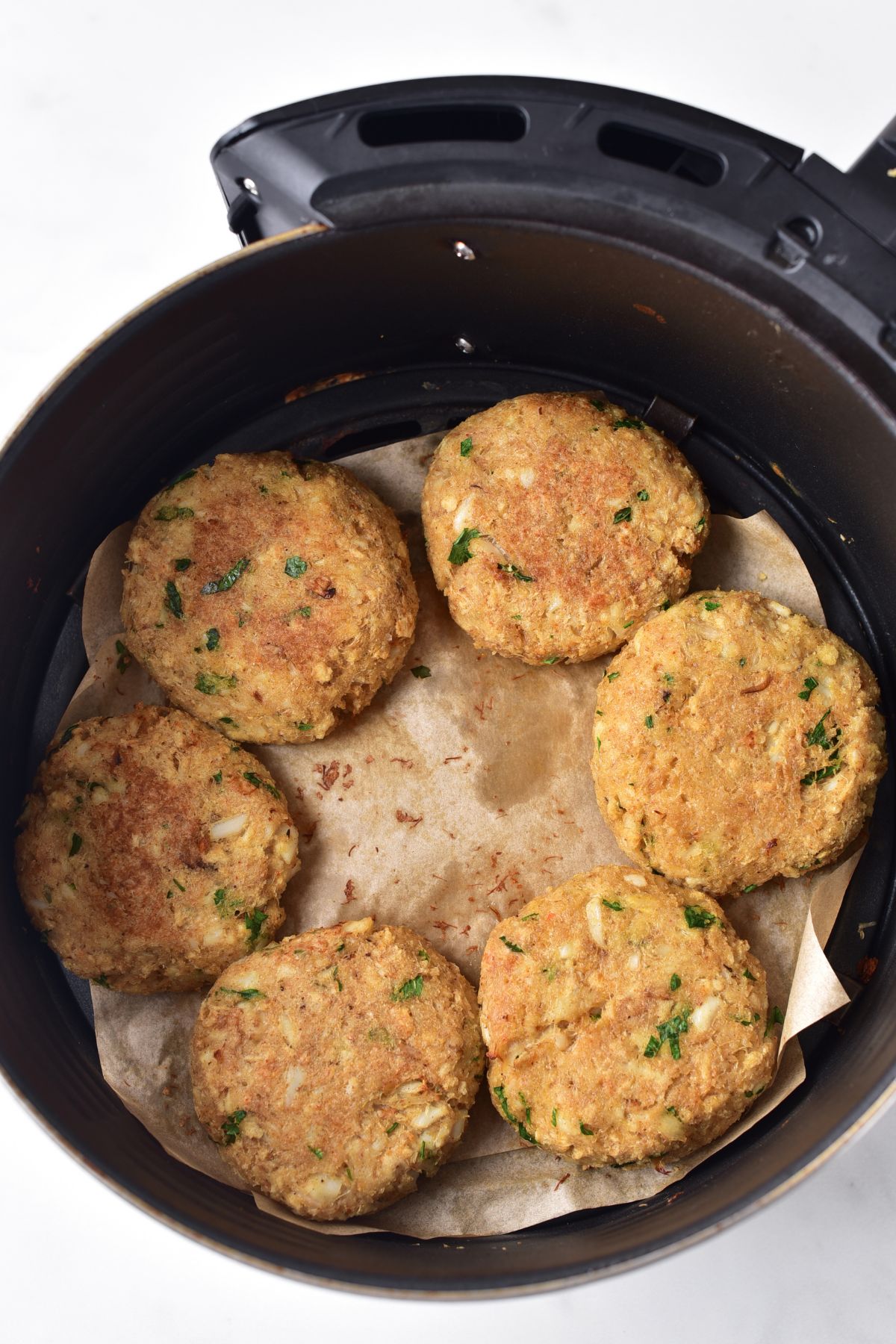 Crab cakes in air fryer basket.