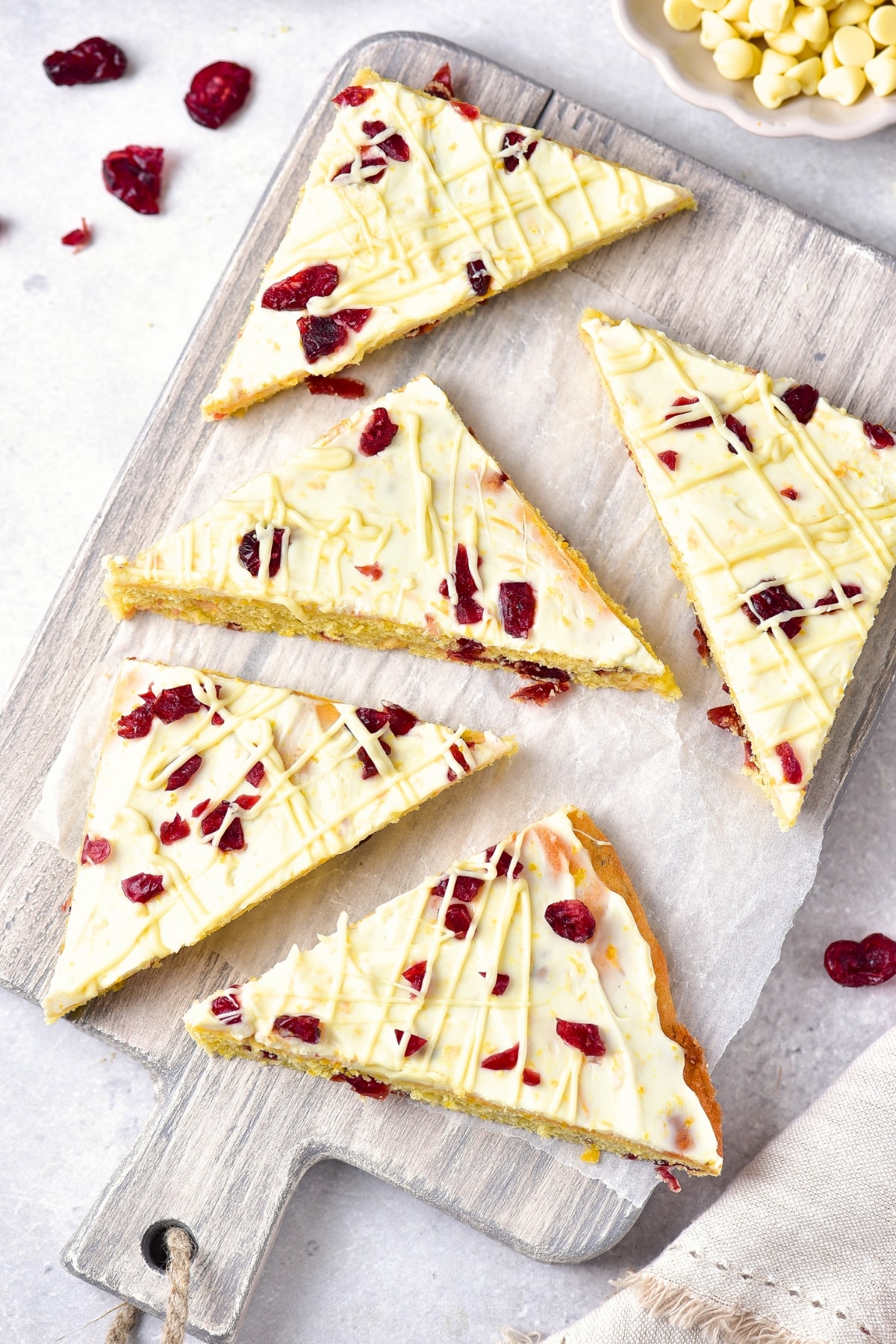 Top down view of cranberry bliss bars on a wooden board.