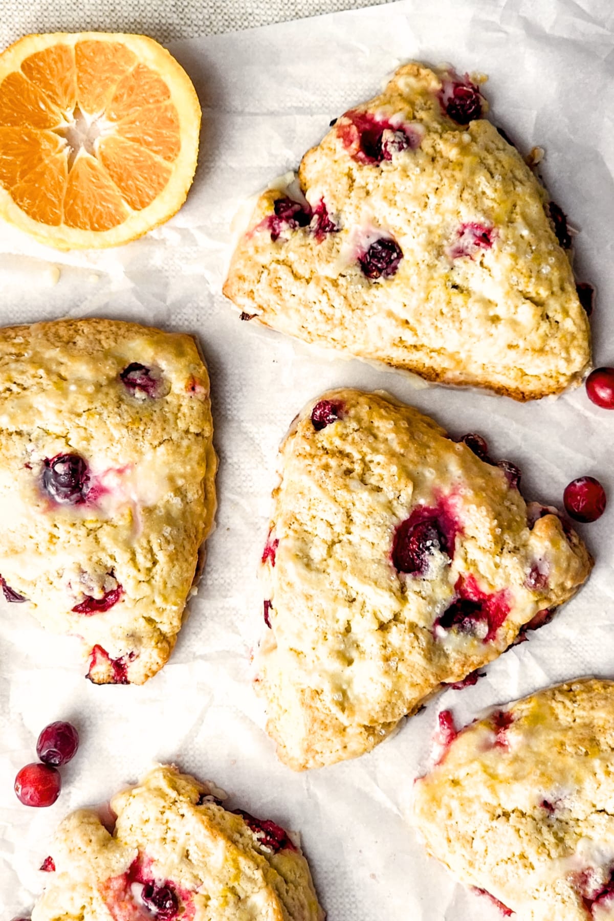 Top down view of gluten-free orange cranberry scones with orange slices and cranberries.