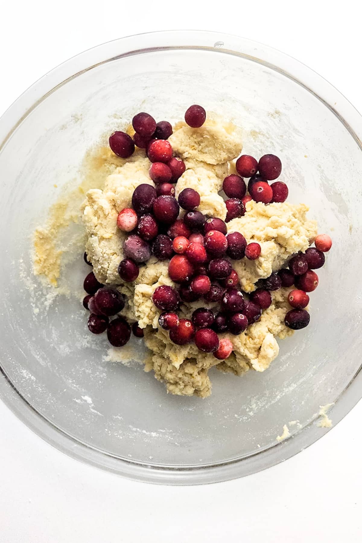 Cranberries on top of scone dough in bowl.