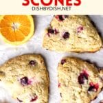 Cranberry orange scones with orange slices on parchment paper.