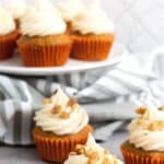 GF carrot cake cupcakes in front of cake stand.