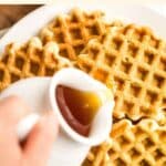 Pouring maple syrup over gluten-free waffles